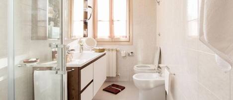 Ein modernes Badezimmer mit Duschkabine aus Glas, Waschtisch mit Spiegel, Toilette und Bidet.
