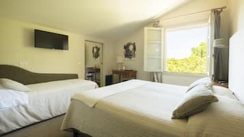 Un dormitorio con dos camas, un televisor montado en la pared y un ventanal con cortinas.