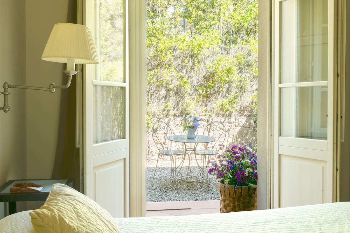 An open door leading to a patio with a table and chairs, a lamp on the wall, and a potted plant.