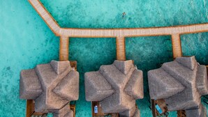 An aerial view of a beachside resort with a wooden pier leading to three thatched-roof lounge areas. - Fihalhohi Maldives (Fihalhohi Island)