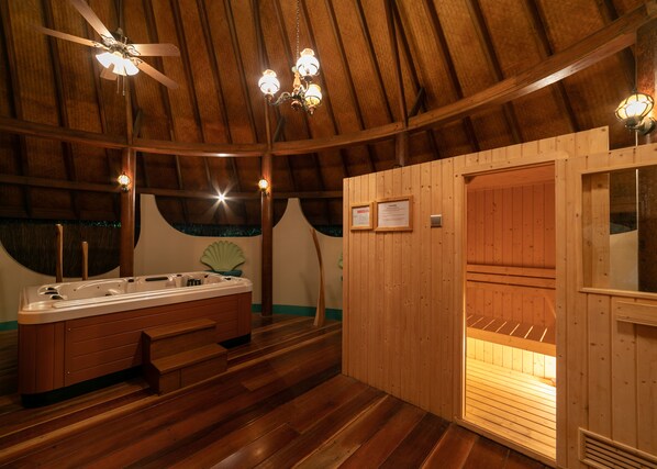 Un sauna de madera con un banco, una pared de madera con una rejilla de ventilación y un ventilador de techo.