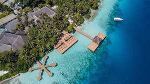 An aerial view of a tropical resort with a beach, palm trees, and a boat dock. - Fihalhohi Maldives (Fihalhohi Island)