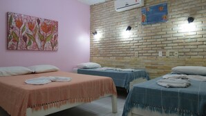 A hotel room with two beds, a pink wall, and a brick wall with an air conditioner and wall art. - Canto do Mar (Ipojuca)
