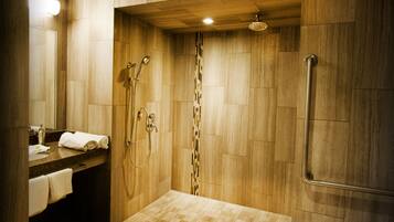 Un baño moderno con paredes de madera, ducha con puerta de cristal y tocador con perchero.