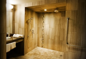 A modern bathroom with wooden walls, a shower with a glass door, and a vanity with a towel rack.