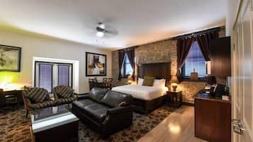 A hotel room with a bed, two sofas, a coffee table, a fireplace, and a television.