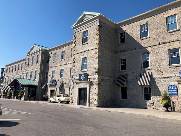 A historic stone building with multiple windows and a green awning.