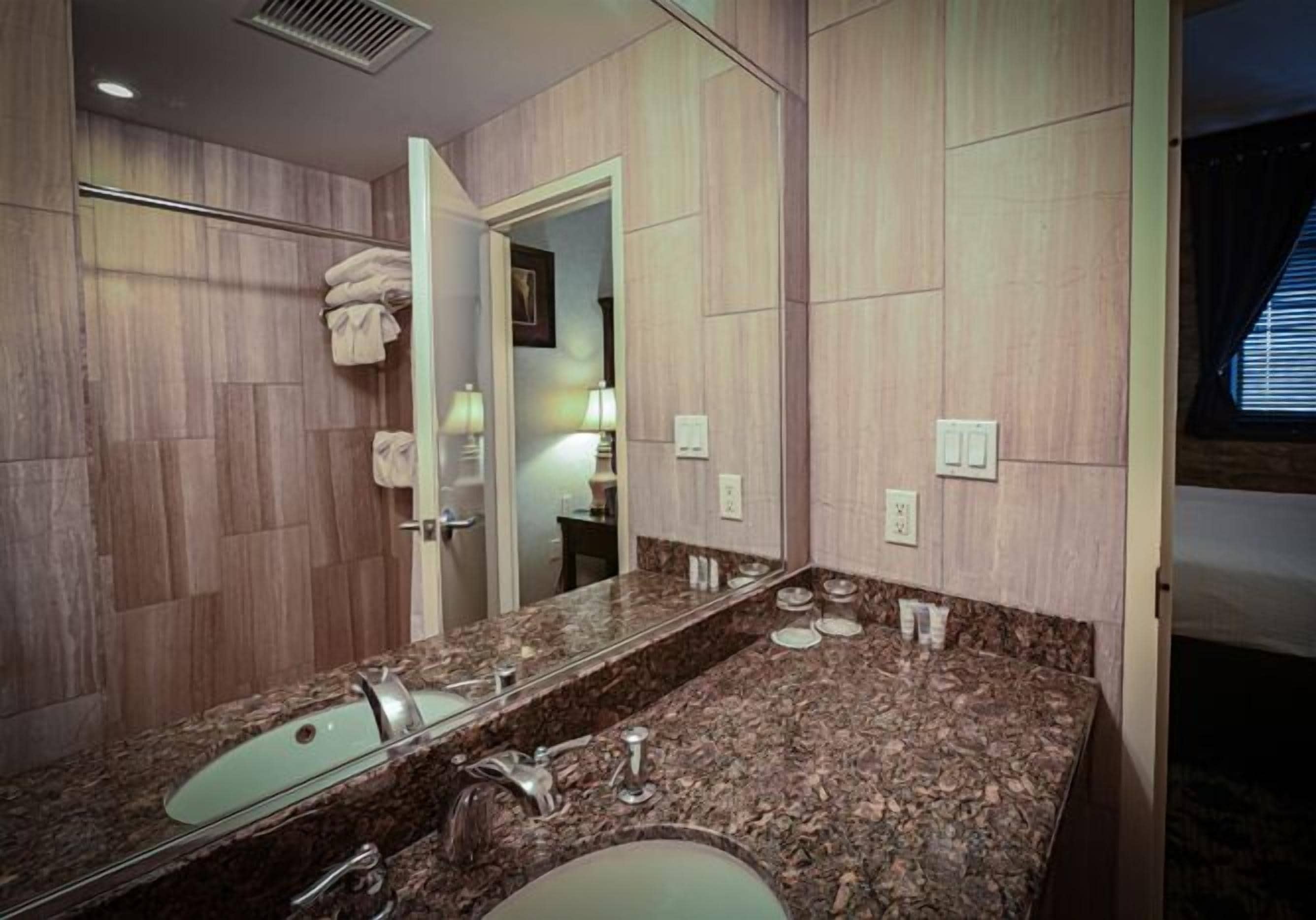A bathroom with a large mirror, two sinks, and a shower area.