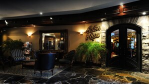 Um hall com piso de pedra, área de estar com sofá e cadeiras, um espelho grande e uma placa com a inscrição 'Salute & Spa'.
