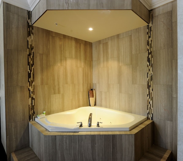 A corner bathroom with a freestanding bathtub, wooden paneling, and a small decorative vase.