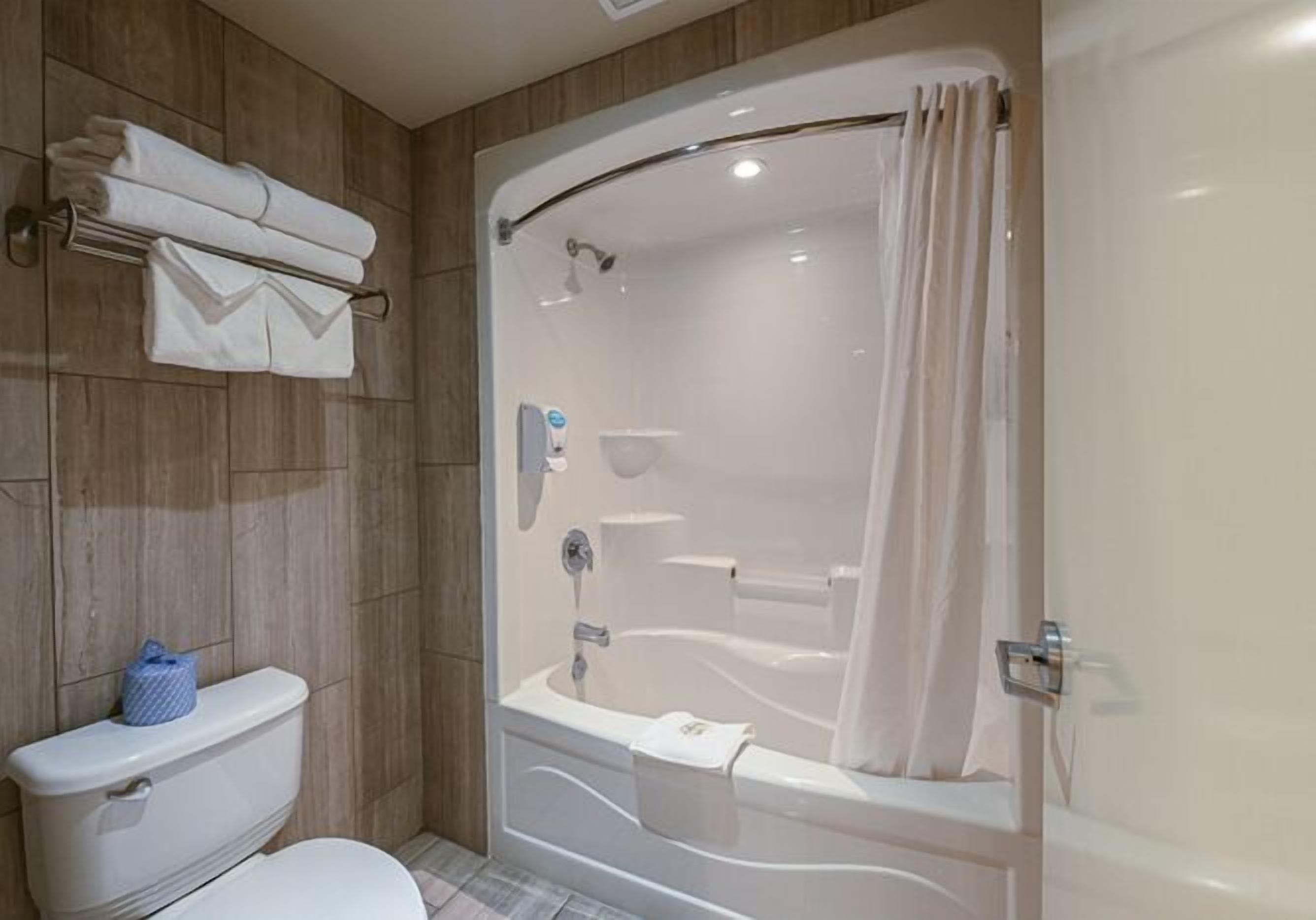 A modern bathroom with a toilet, a shower with a glass door, and a towel rack with folded towels.
