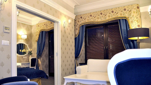 A hotel room with a sitting area, a small table, a mirror, and a wardrobe. - SleepWalker Boutique Suites (Wroclaw)