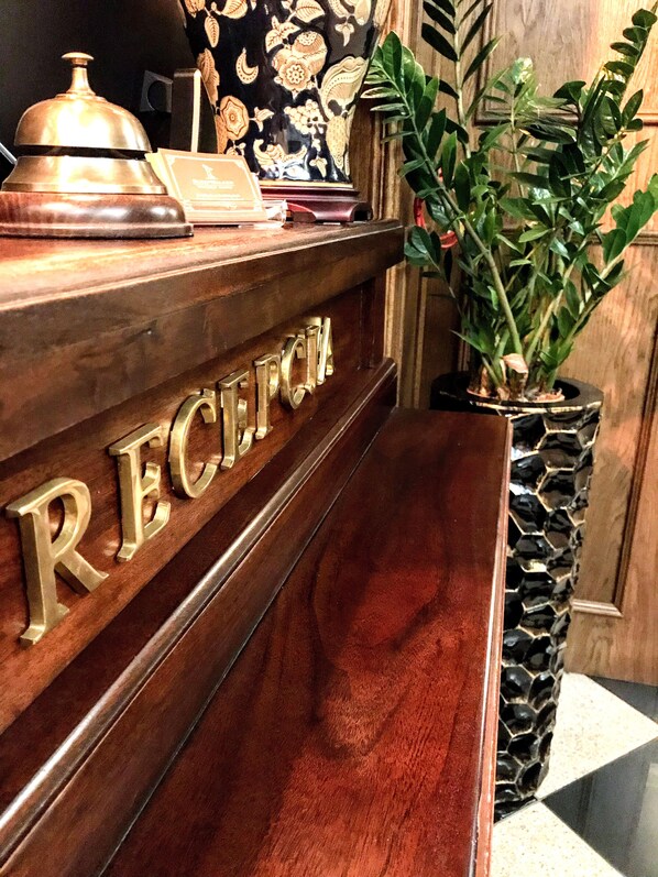 A reception desk with a wooden finish and a nameplate that reads "RECEPTION". - SleepWalker Boutique Suites (Wroclaw)