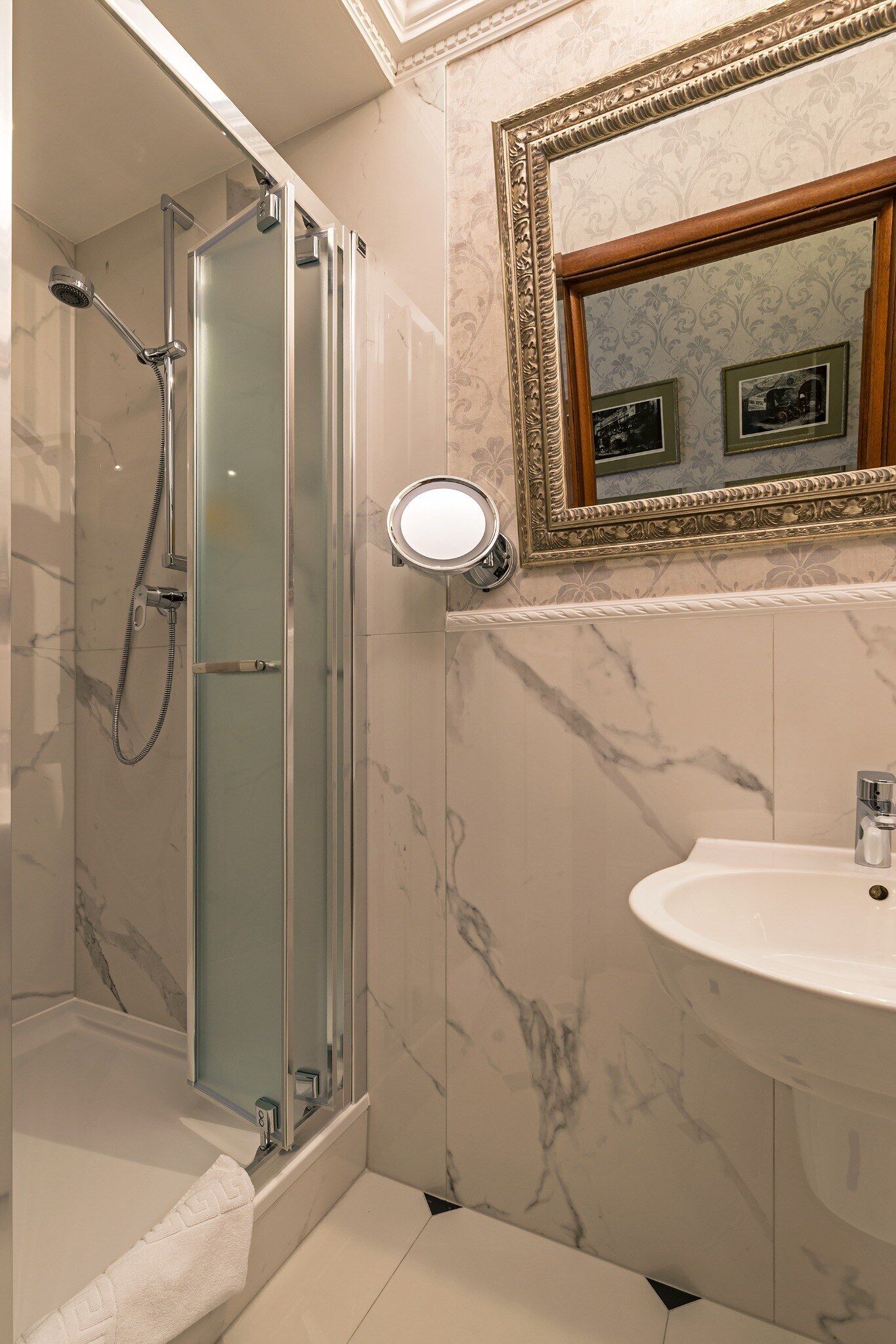 A bathroom with a glass-enclosed shower, a sink with a mirror above it, and a towel rack.