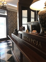 A reception desk labeled "RECEPTORIA" with a computer, a lamp, and a decorative vase.