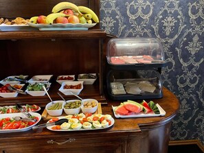 A buffet with various food items including fruits, salads, and meat. - SleepWalker Boutique Suites (Wroclaw)