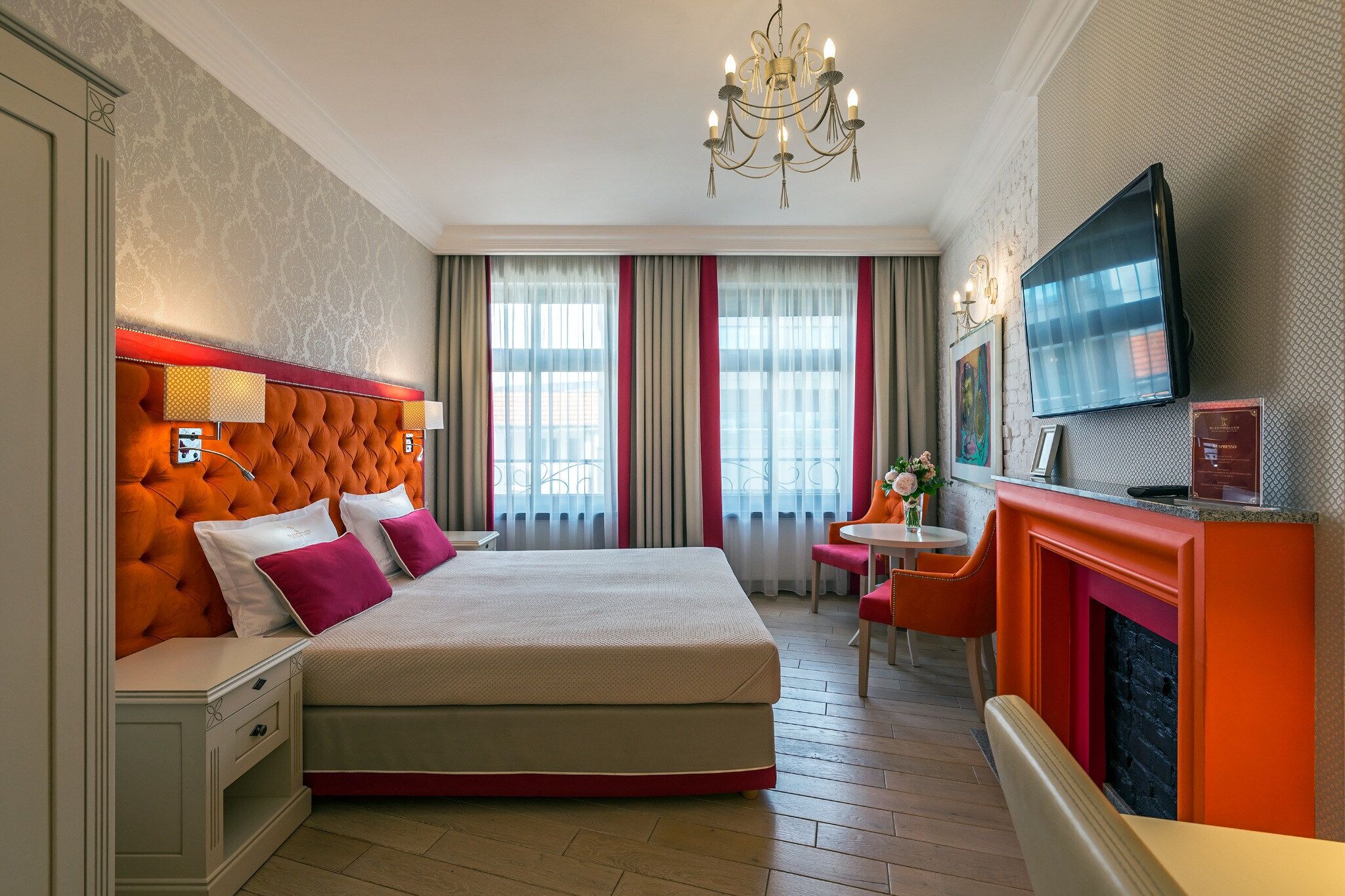 Habitación de hotel con una cama grande, televisión, chimenea y escritorio con silla.