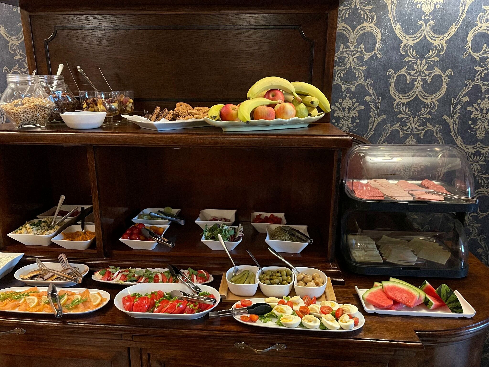 A buffet table with various food items and utensils.
