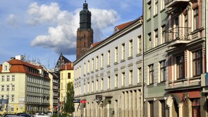 A street with historic buildings, a prominent tower, and parked cars. - SleepWalker Boutique Suites (Wroclaw)
