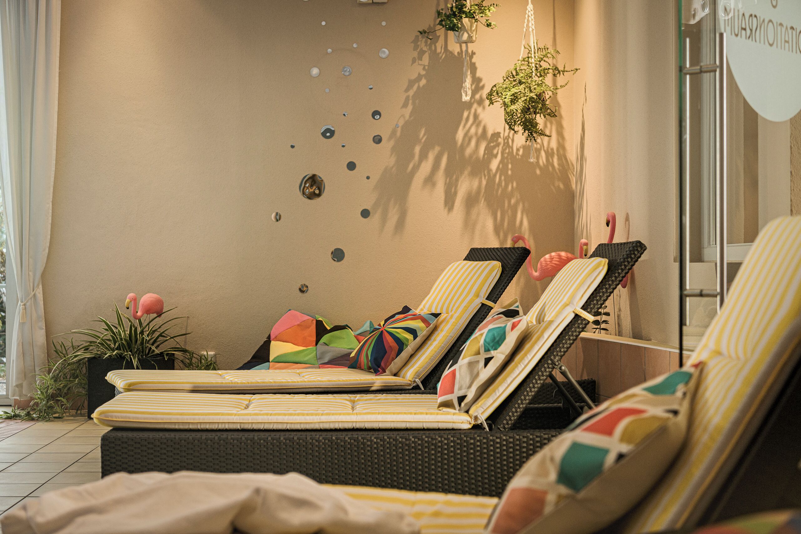 A sunlit room with three reclining chairs, each with striped cushions, a potted plant, and decorative wall elements.