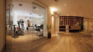 Un gimnasio moderno con máquinas de cardio, una zona de recepción y un comedor con sillas transparentes.