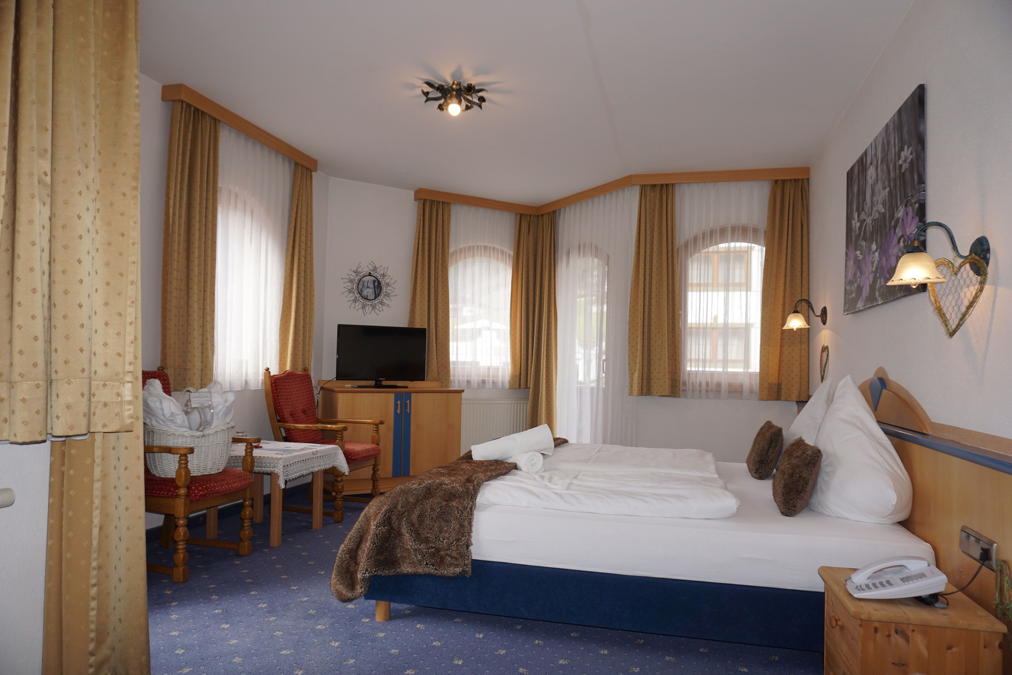 A hotel room with a bed, a desk with a chair, a television, and a telephone.