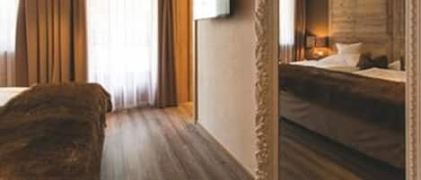 Habitación de hotel con una cama grande, un televisor instalado en la pared y vista del cuarto en un espejo.