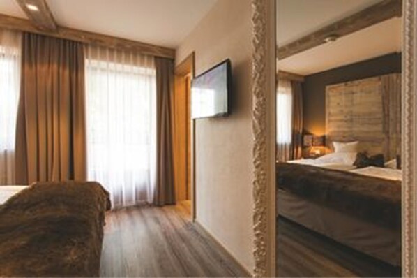 Habitación de hotel con una cama grande, un televisor instalado en la pared y vista del cuarto en un espejo.