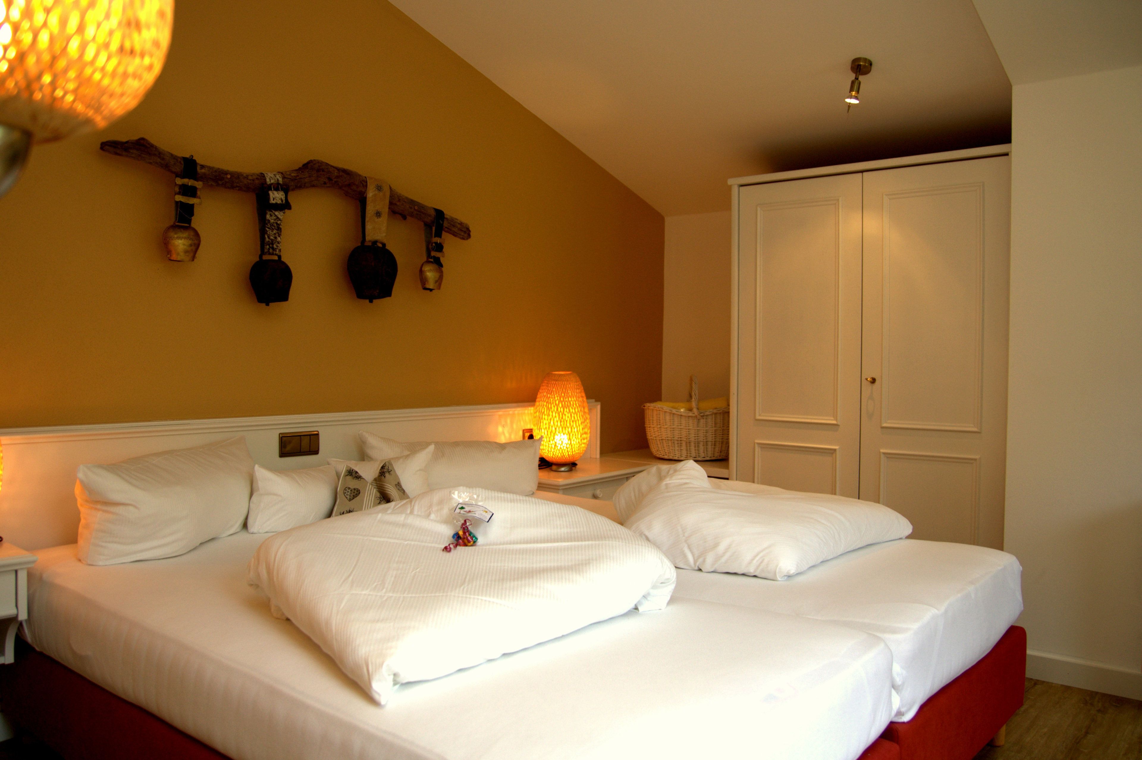 Een hotelkamer met een groot bed, een nachtkastje, een lamp, een wandplank met decoratieve objecten en een kledingkast.