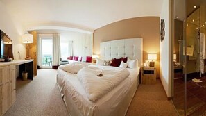 Amplia habitación de hotel con una cama grande, un escritorio y vistas al exterior.