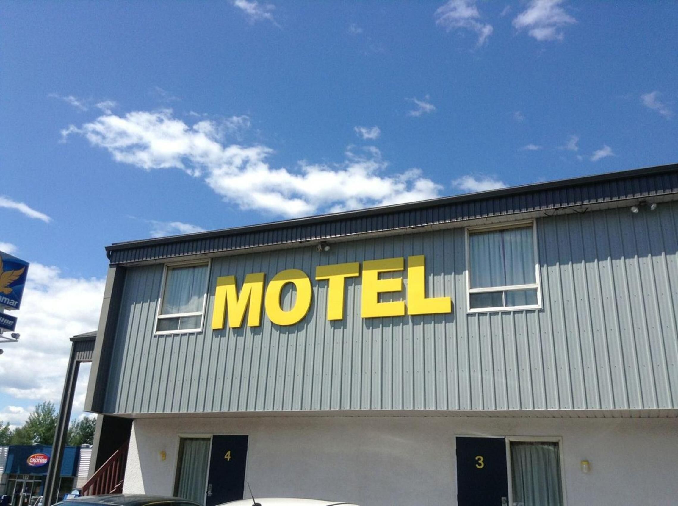 A motel with a prominent 'MOTEL' sign on the facade, featuring two windows and a door with the number '4' visible.