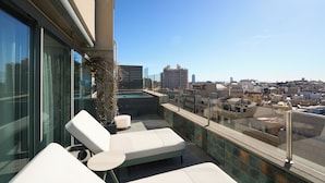 Una terraza en la azotea con sillones, una mesita y vistas a la ciudad.