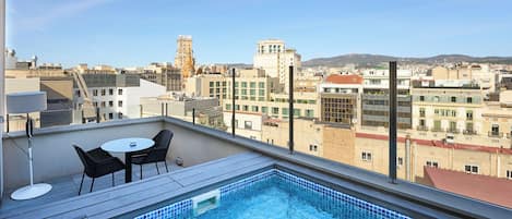 A rooftop pool with a view of the cityscape, including buildings and a tower.