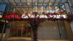 Entrada de un hotel con un gran letrero que dice "HOTEL CATALONIA SQUARE" y un arreglo floral decorativo.