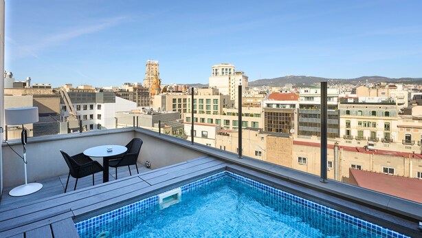 Una piscina en la azotea con vistas a la ciudad, incluyendo edificios y una torre.