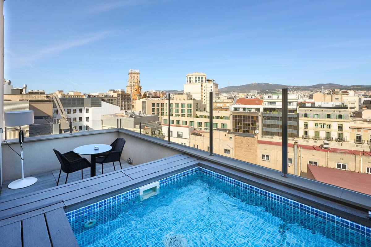 A rooftop pool with a view of the cityscape, including buildings and a tower.