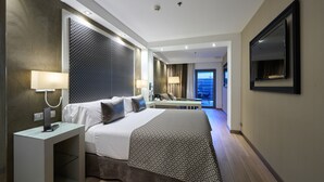 Una habitación de hotel moderna con una cama grande, un escritorio, un televisor y vistas a la ciudad.