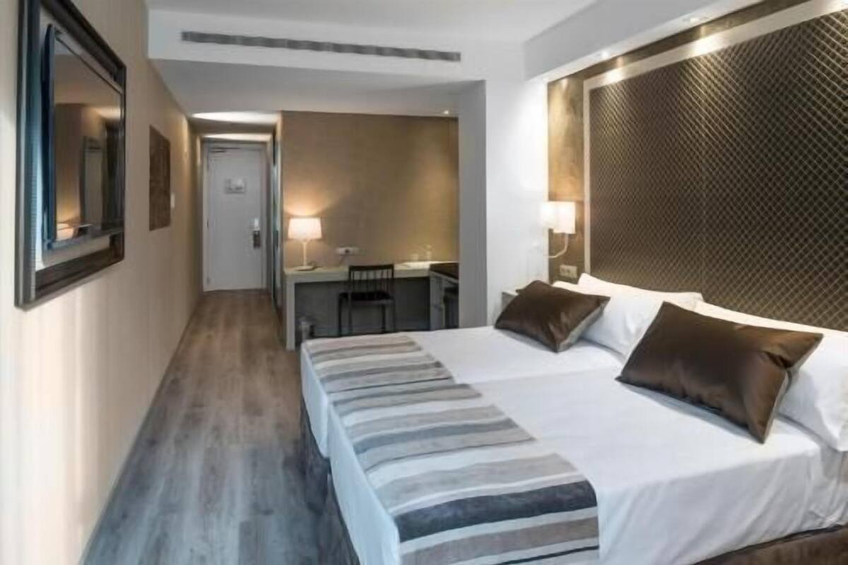 A hotel room with a bed, a desk, and a chair.