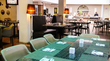 A restaurant with multiple tables set for dining, equipped with green placemats and cutlery.