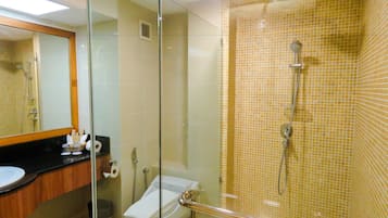 A modern bathroom with a glass shower enclosure, a toilet, and a sink with toiletries.