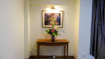 A room with a wooden console table, a vase with flowers, and a framed picture on the wall.