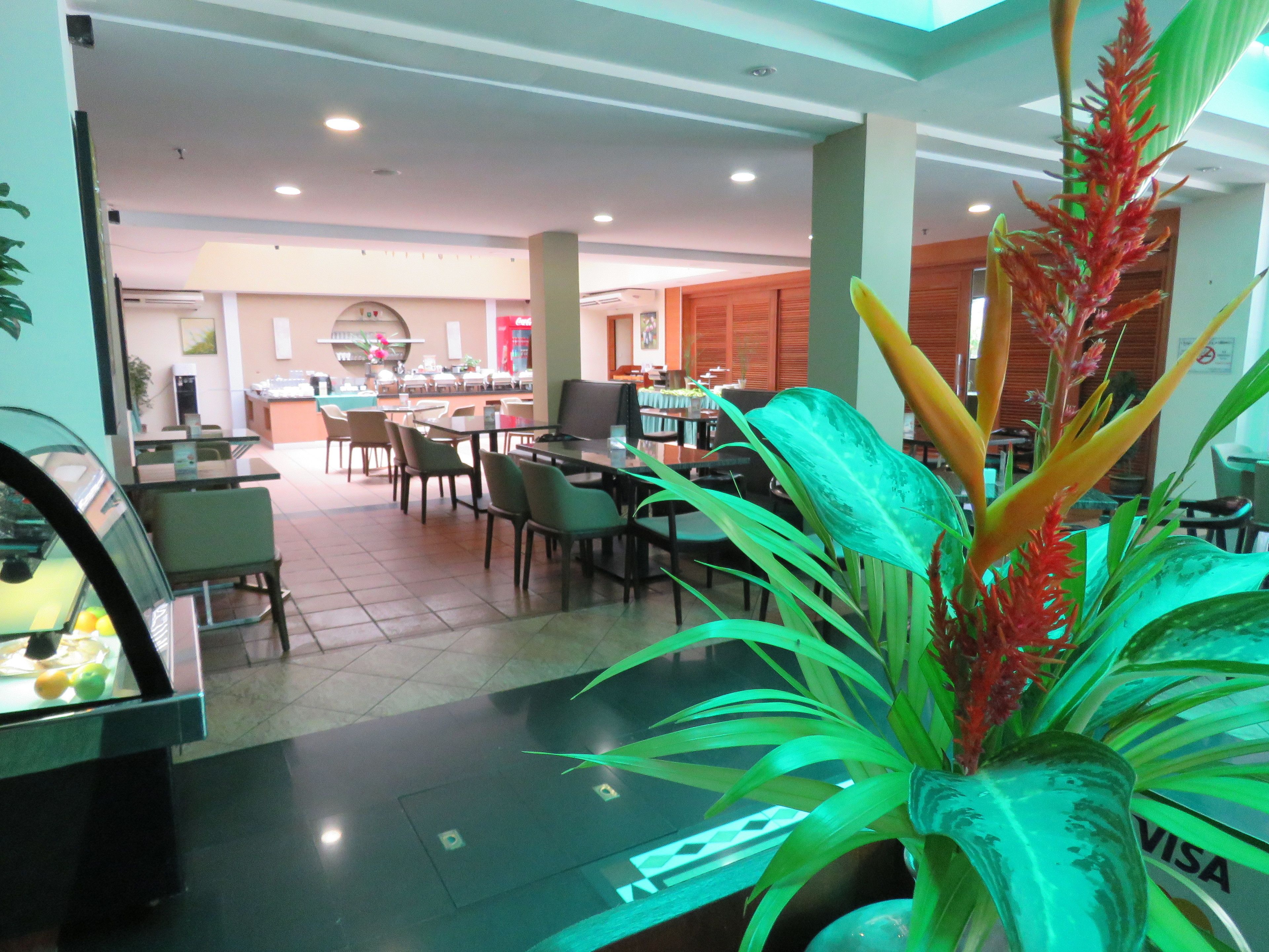 A spacious lobby with a reception desk, seating area, and a view of the restaurant in the background.