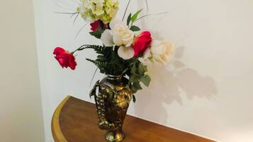 A vase with flowers on a wooden table against a white wall.