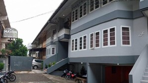 Un edificio de varios pisos con fachada gris, una escalera visible y una motocicleta estacionada.