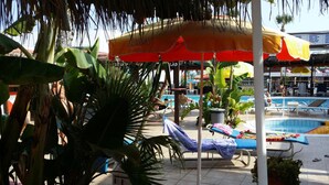 A poolside area with lounge chairs, umbrellas, and potted plants. - Kkaras Hotel (Ayia Napa)