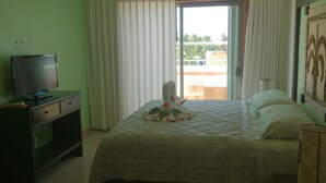 Habitación de hotel con cama, televisión sobre un escritorio y vista al exterior por la ventana.