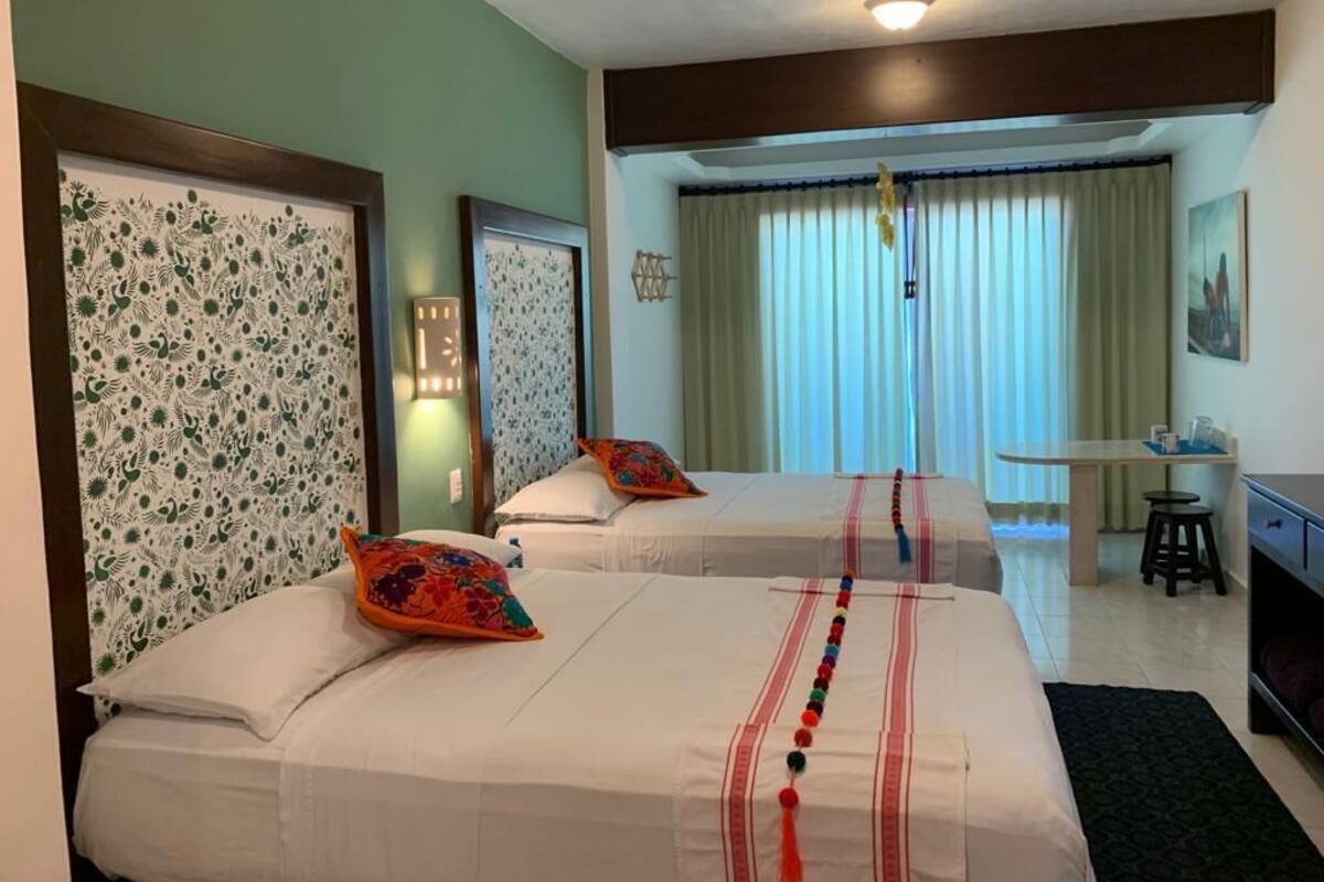 A hotel room with two beds, a desk, and a chair.