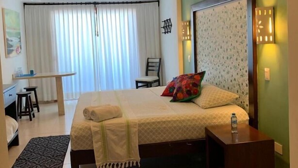 Una habitación de hotel con cama, mesita de noche y unidad de aire acondicionado.