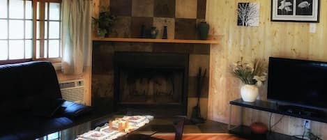 Een woonkamer met een open haard, een bank, een salontafel en een televisie.