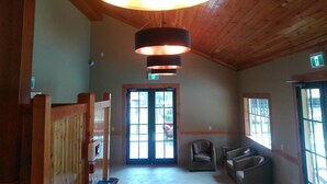 A spacious lobby with a wooden ceiling, a large circular ceiling light fixture, and a comfortable seating area with wicker chairs. - Fairmont Mountain Bungalows (Fairmont Hot Springs)